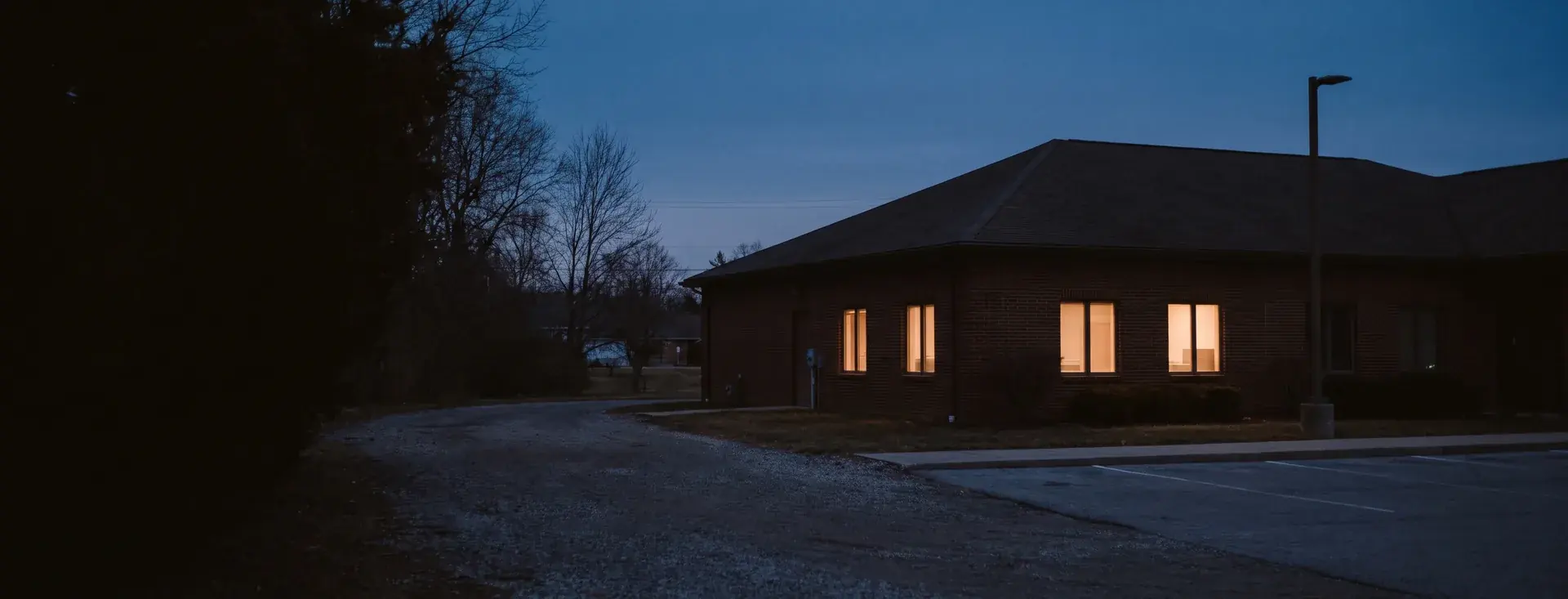 A small suburban police station at dusk with the windows lit